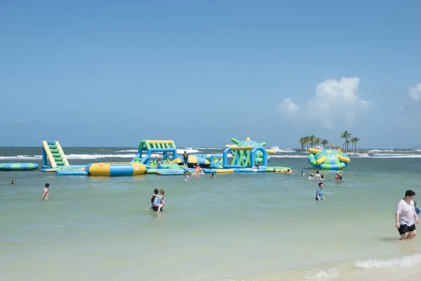 Families enjoying the inflatable water park at the beach