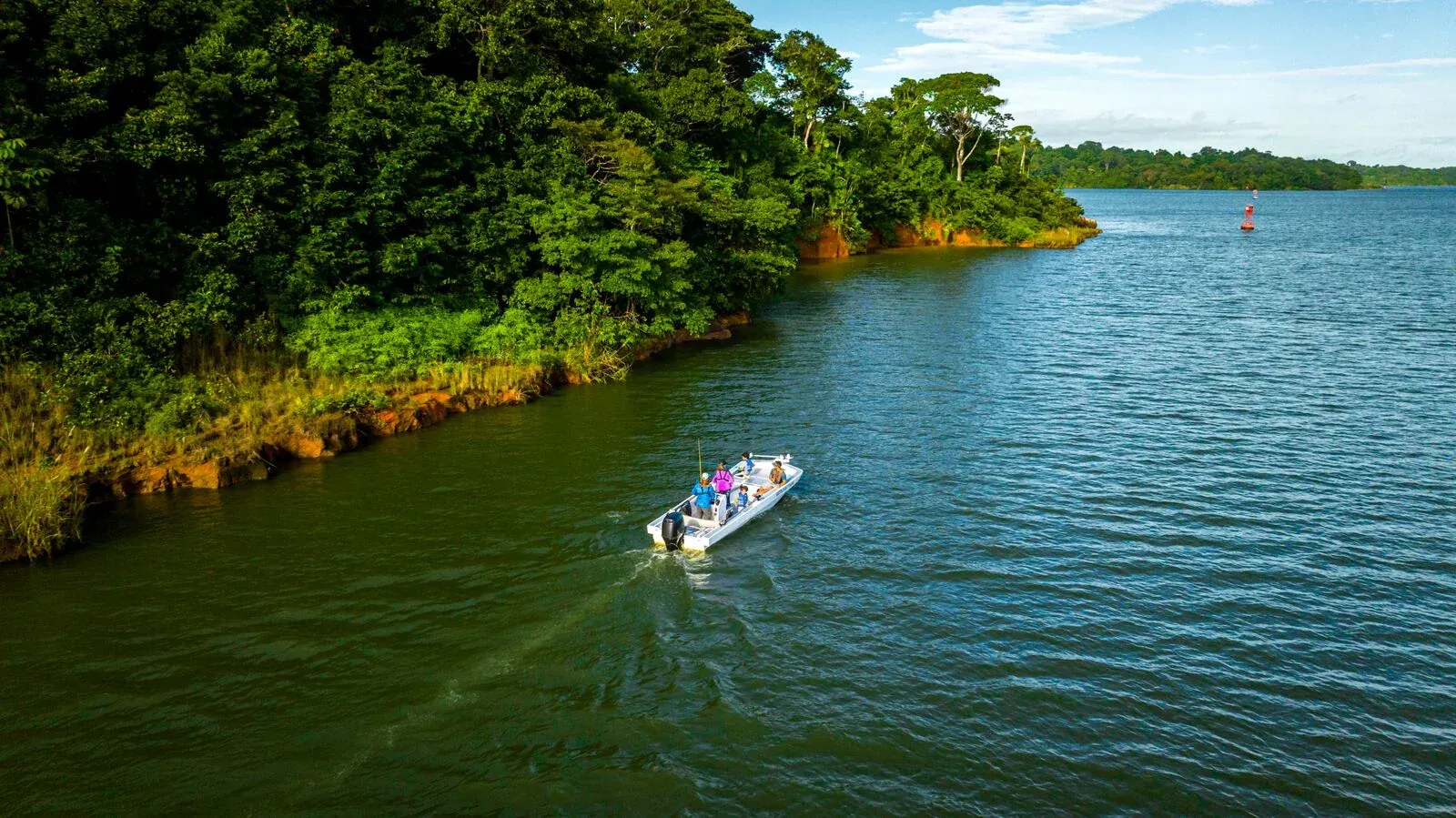 Small fishing boat crossing Gat&uacute;n Lake between forested islands
