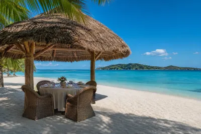 Palapa con techo de paja que da sombra a una mesa de comedor en una playa de arena blanca en Panamá