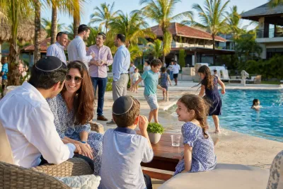 Jewish families enjoying a Yeshiva Week vacation together beside a tropical pool