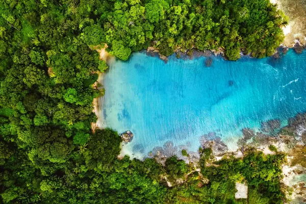 Aerial view of Playa Escondida — a hidden turquoise cove framed by rainforest