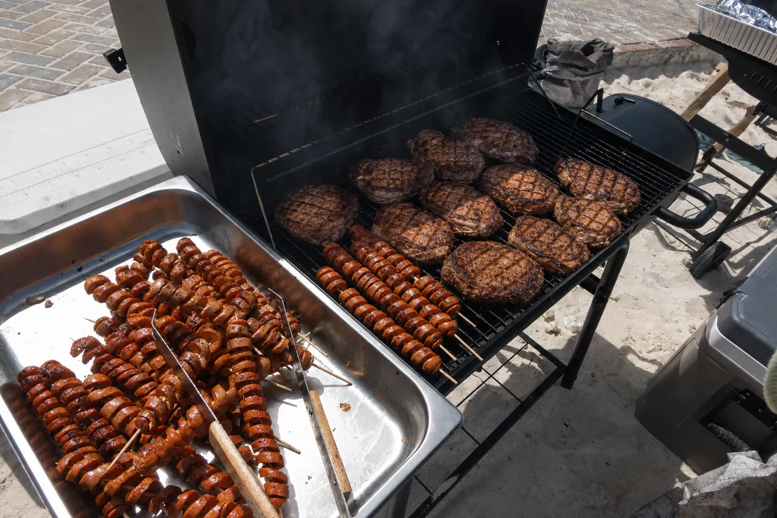 Steaks grillés et brochettes de saucisses cuisinant au barbecue de la plage