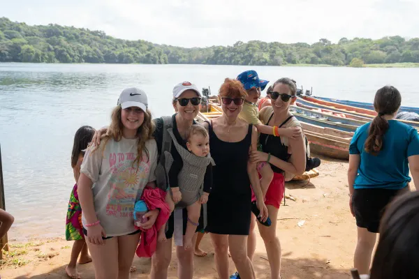 Family group by the river with traditional canoes